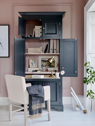home office area with freestanding desk with storage, chair, basket, pink wall, blue unit