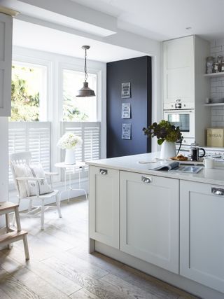 Grey kitchen cabinets and white tiled backsplash and shutters