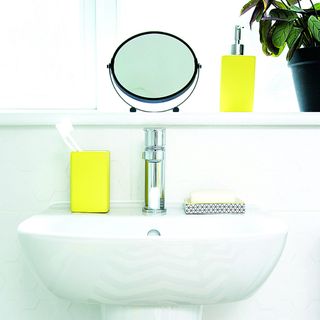 Bathroom sink with a magnifying mirror and yellow accessories