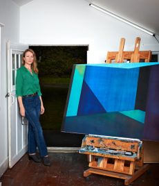 Artist Karin Schaefer photographed in her studio, alongside Dark Matter, 2022 (oil on panel), currently on view at Sears Peyton Gallery, New York