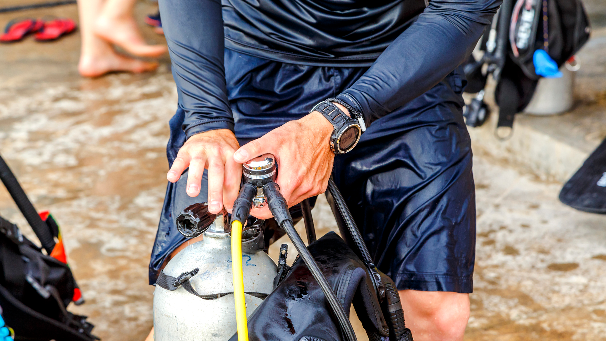 A close up of a diver putting hoses on a scuba tank