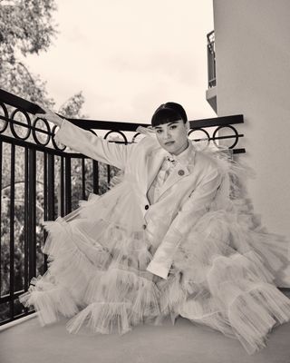 Devery Jacobs on the balcony of her hotel before the emmys wearing a white suit with tulle all over