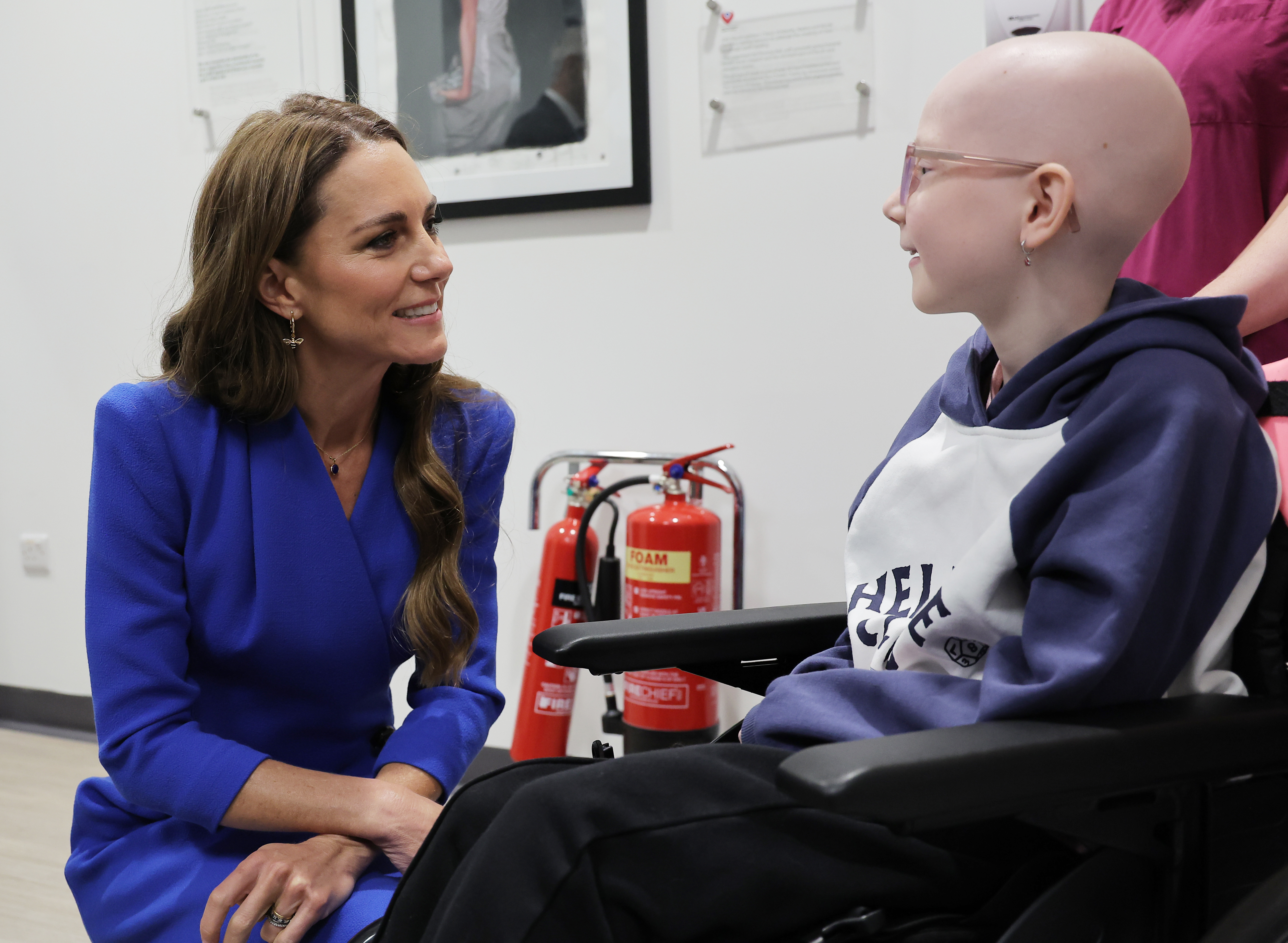 Princess Kate kneeling and speaking to a child in a wheelchair