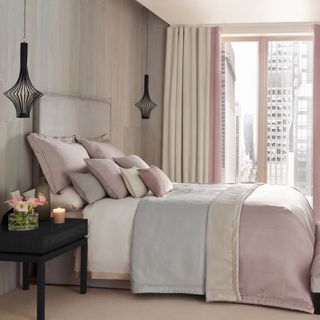 how to make a guest room look more expensive, apartment/hotel chic style bedroom in pastel pink, cream and pale grey, black side table and hanging pendants, cream carpet