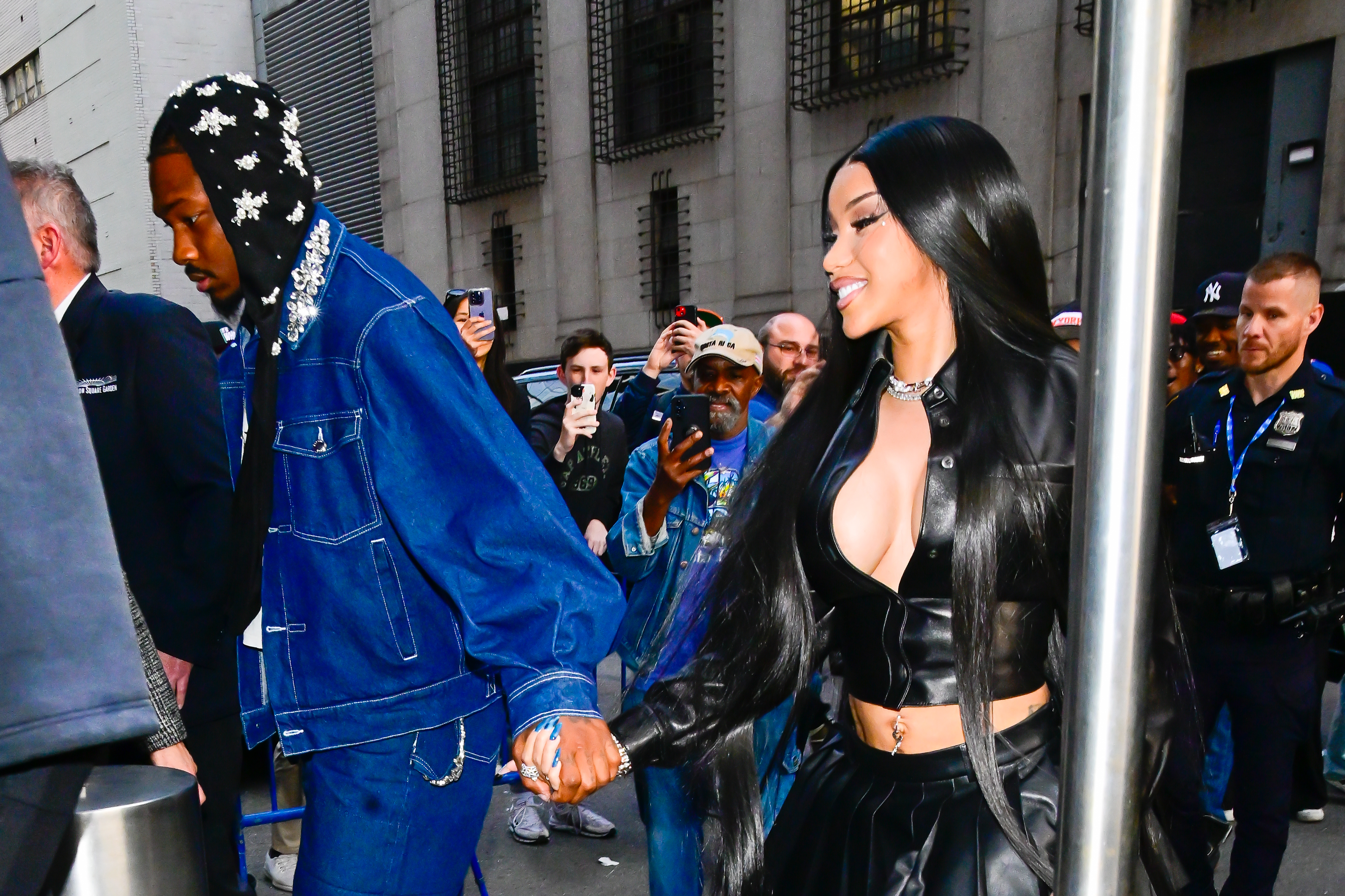 Stefon Diggs in a blue denim outfit and embellished hoodie and Cardi B in a black leather outfit are seen at Madison Square Garden on May 12, 2025 in New York City.