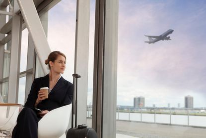 A young businesswoman sips coffee as she waits in a airport.
