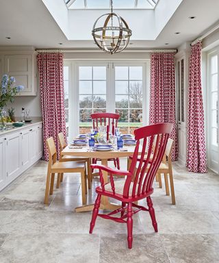 Dining room curtain ideas with a neutral country kitchen, red chairs, blue tableware and red and white patterned curtains