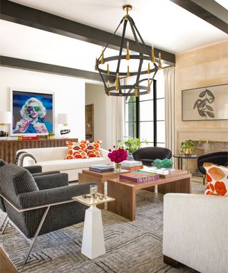 A living room with wooden rafters on the ceiling, a white sofa, a rustic light fixture, and a fireplace