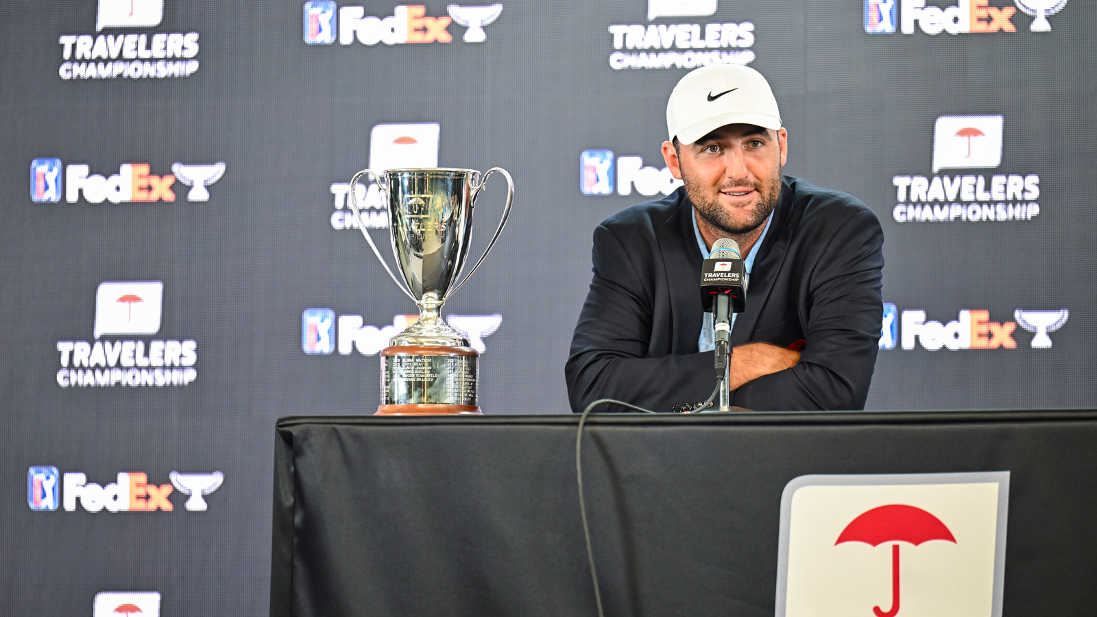 Scottie Scheffler sits next to the Travelers Championship trophy