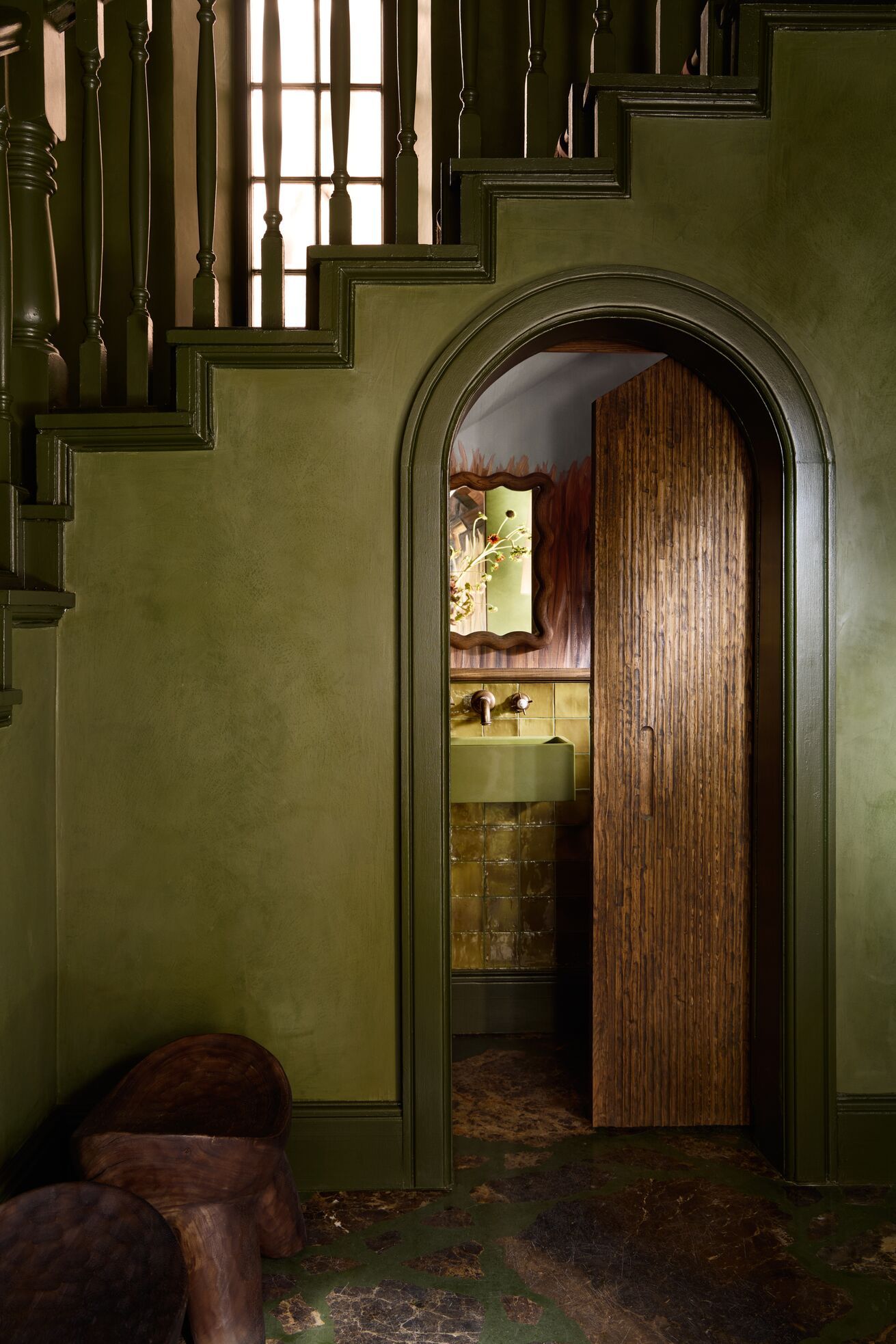 A series of shots capturing a young man dressed in patterned, or color-blocky, clothing, either standing in the sun-lit outdoor areas of a lush hotel, or inside a colorfully decorated suite filled with collectibles, artworks, and textural touches, or the interiors of that very space.