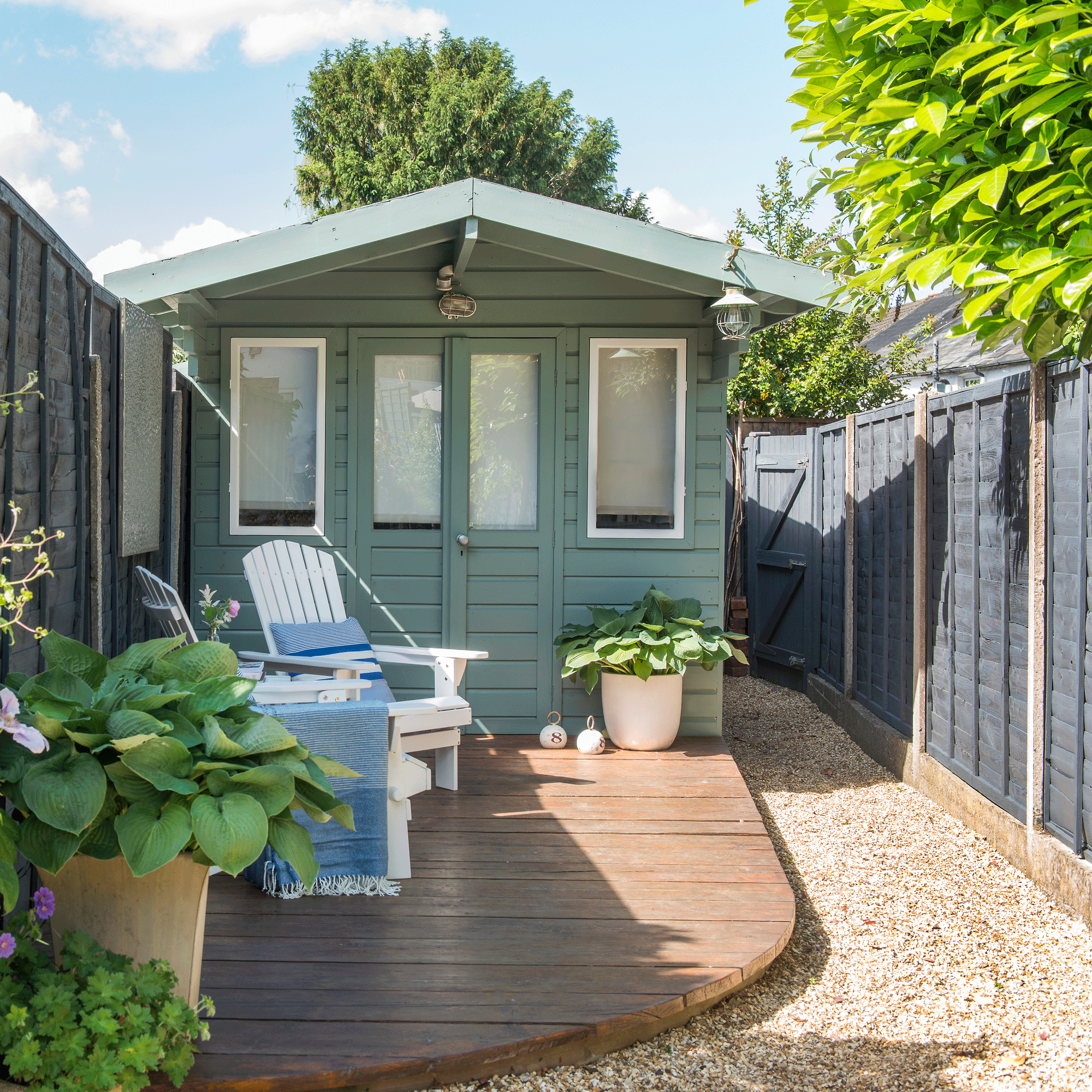 a small garden with a shed surrounded by fencing and a small decked area with a path that wraps around it