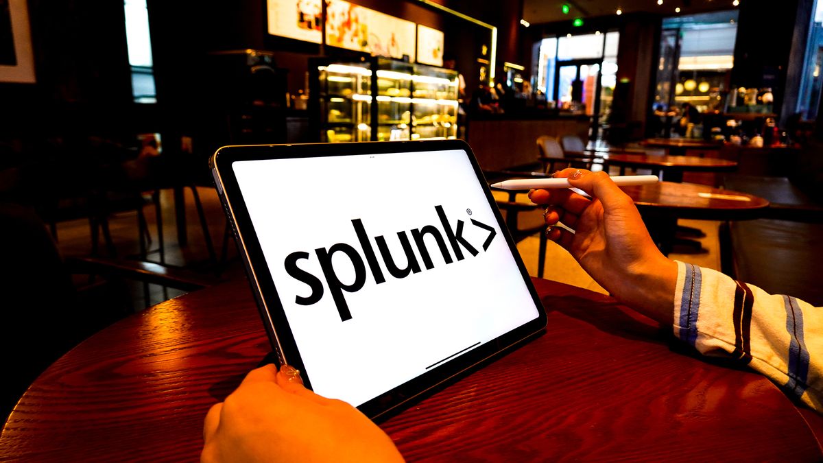 Spunk logo and branding in black coloring pictured on a white background on a tablet, held in a man&#039;s hands in a dimly lit coffee shop.