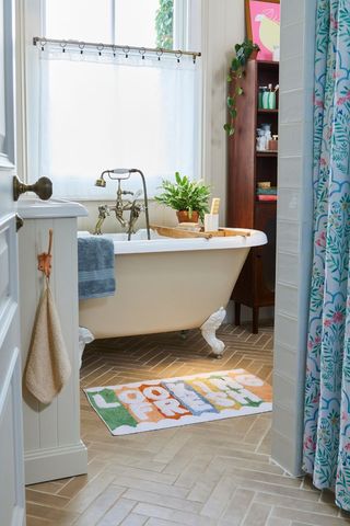 bathroom with white tub and colourful bathmat
