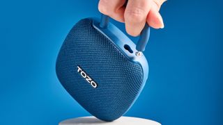 Tozo PE1 speaker in blue with built-in clip photographed on a blue background.