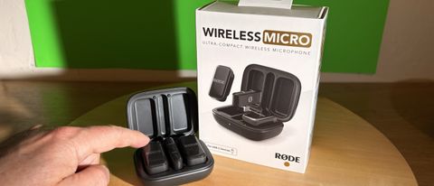 Rode Wireless Micro next to its retail box with a finger pointing to the microphone