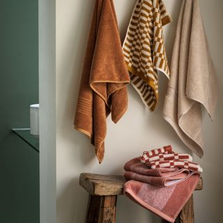 red bath towels hung on pegs and folded on bench