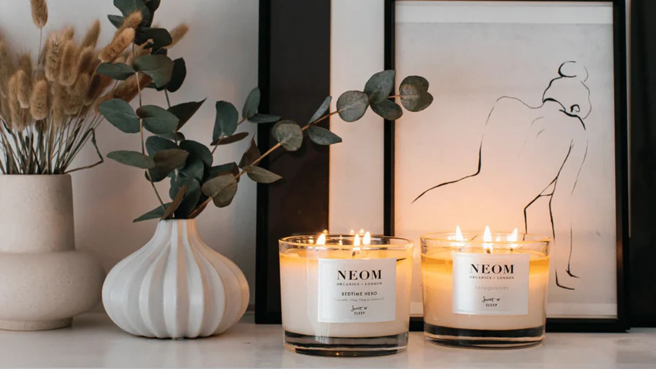 Two NEOM candles on a mantelpiece