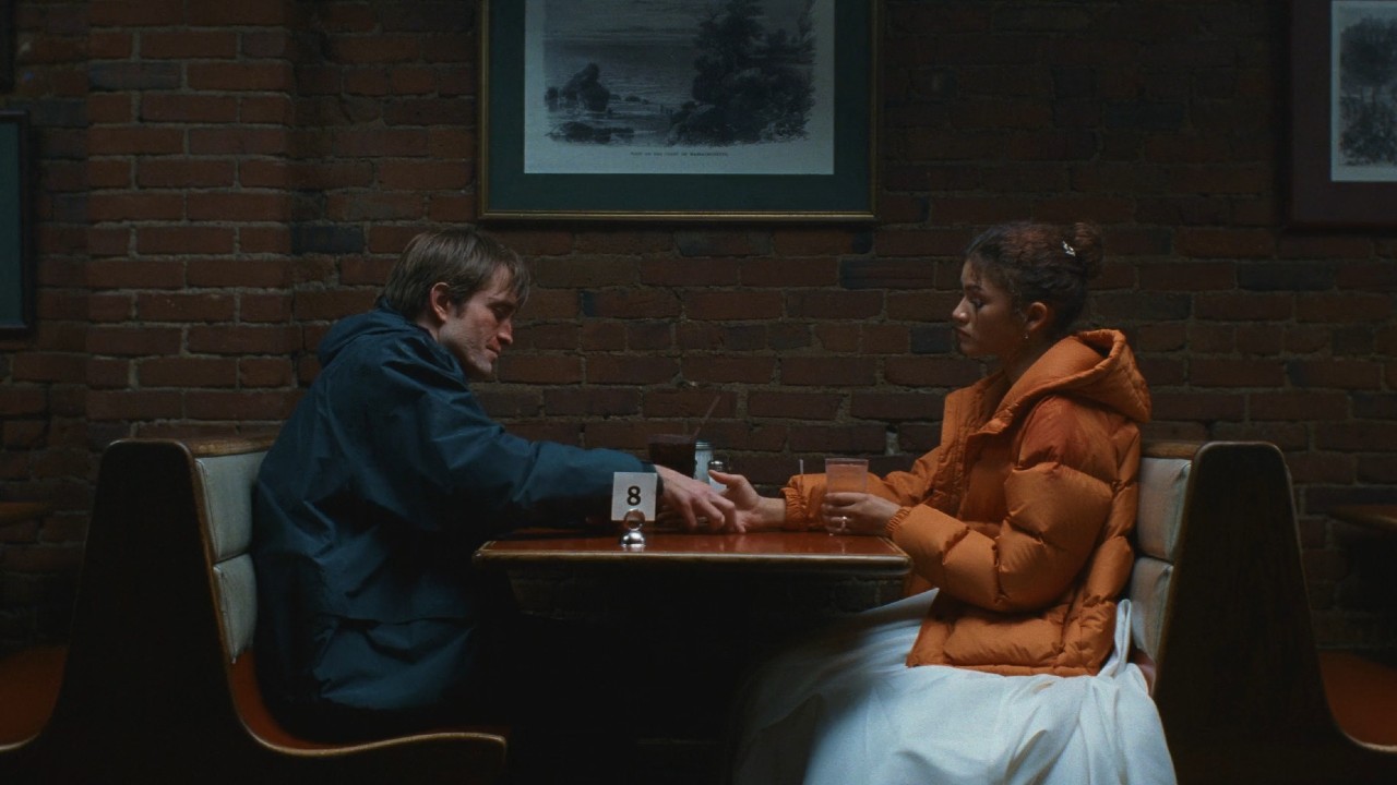Robert Pattinson holding Zendaya's hand in The Drama. 
