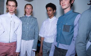 A row of models pose for a picture against a white backdrop