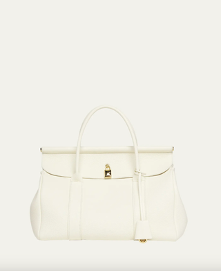 a white loro piana bag in front of a plain backdrop