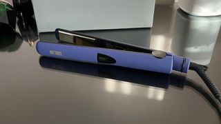 The Hot Tools Pro Signature Digital Straightener lying on its side on a glass countetop
