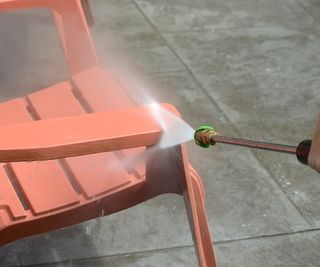 Pressure washer cleaning a red chair