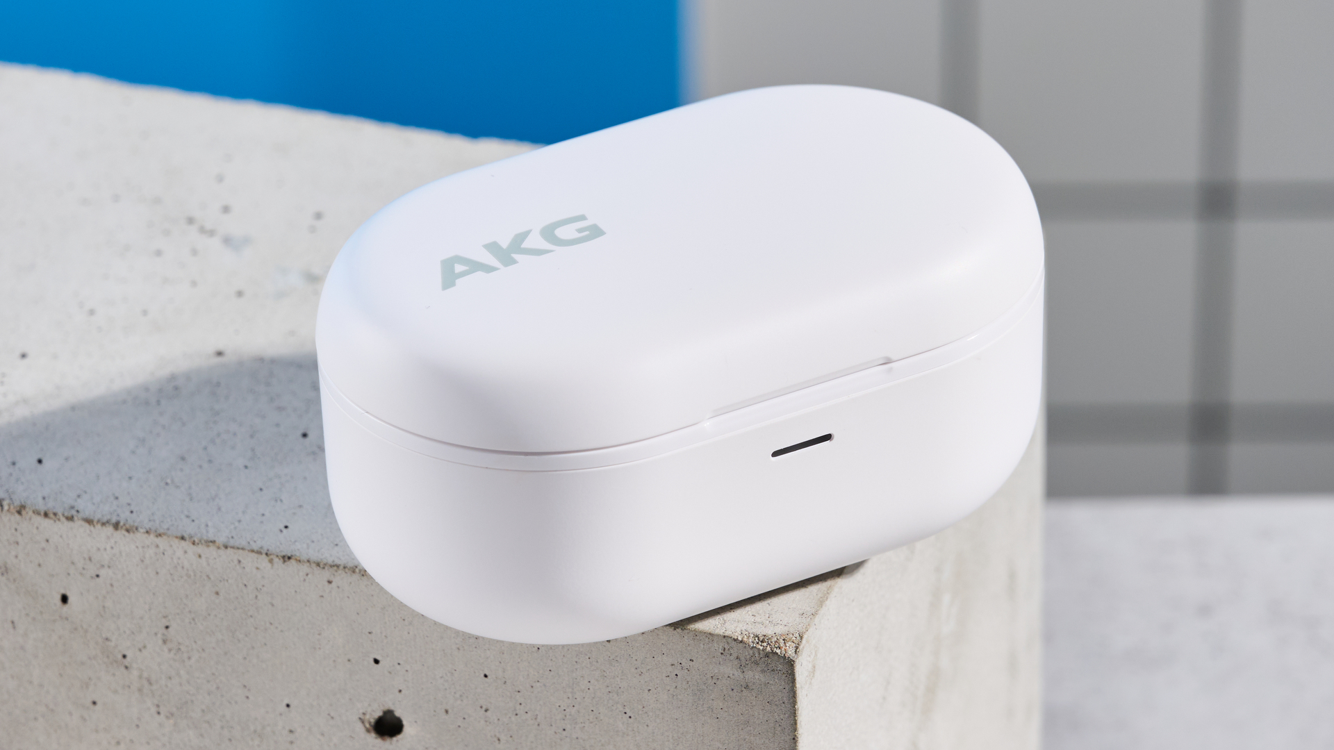 the akg n5 hybrid earbuds by harman in white, shown in their charging case with accessories and without