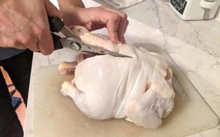 cutting a chicken using a pair of kitchen shears
