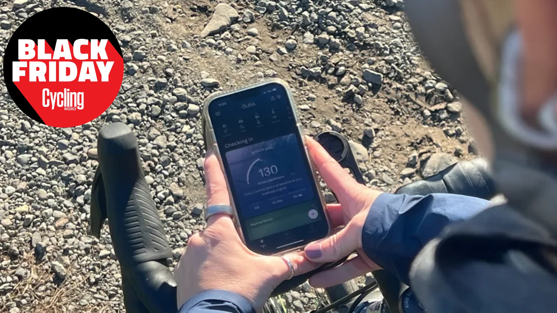 The Oura Ring on the finger of our North American Editor while she stands over her handlebars looking at the Oura App on her phone