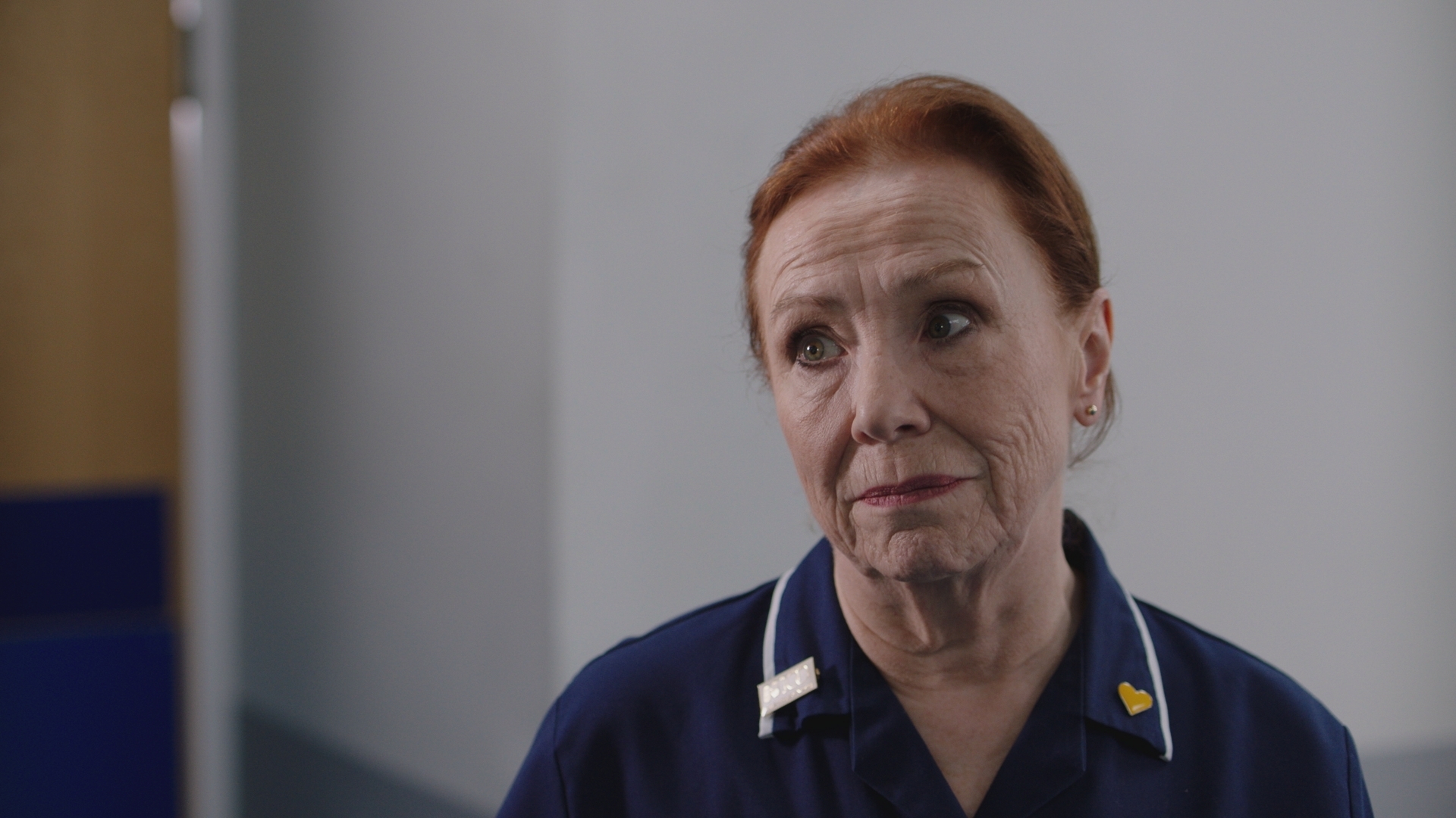 Siobhan at work, wearing her navy uniform looking concerned and thoughtful at someone off camera.