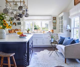 kitchen with blue and white cabinets white sofa and rug and dark wood floor