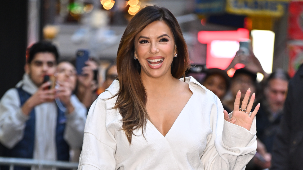 Eva Longoria waving while wearing a bronze french manicure