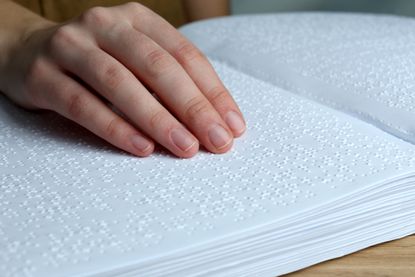 A woman reads a book in Braille.