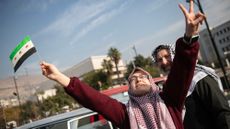 People celebrate in the street after Syrian rebels captured the city of Damascus