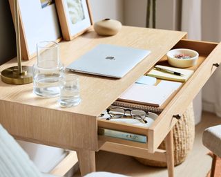 Wooden desk with laptop and water glasses on top