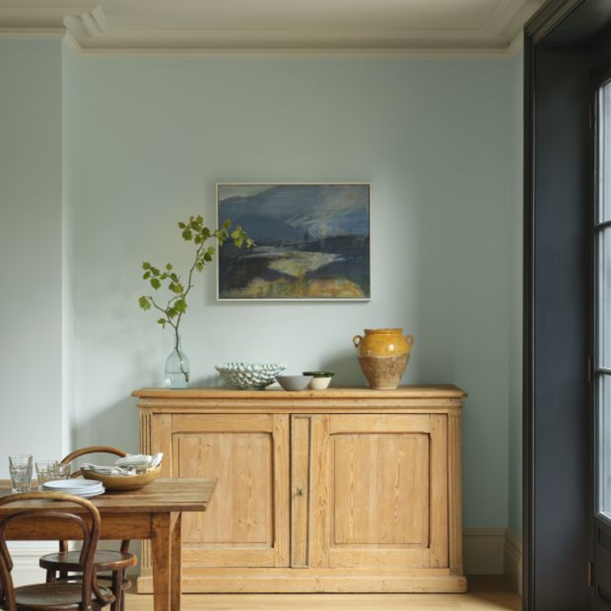 A dining room painted in Benjamin Moore's Crystal Blue 2051-70 shade with the ceiling and skirting boards in White Blush 904