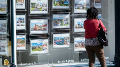 Woman looking at property to buy in estate agents window