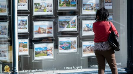 Woman looking at property to buy in estate agents window