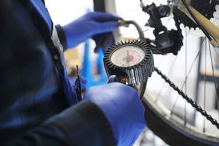A bike mechanic uses an air compressor to pump up tires