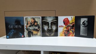 Various 4K Blu-ray steelbooks stood up on a white table 