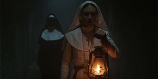 The Nun Taissa Farmiga Sister Irene holding a lantern creepy nun behind her