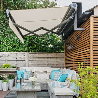Retractable awning installed on pergola garden structure covering outdoor seating area