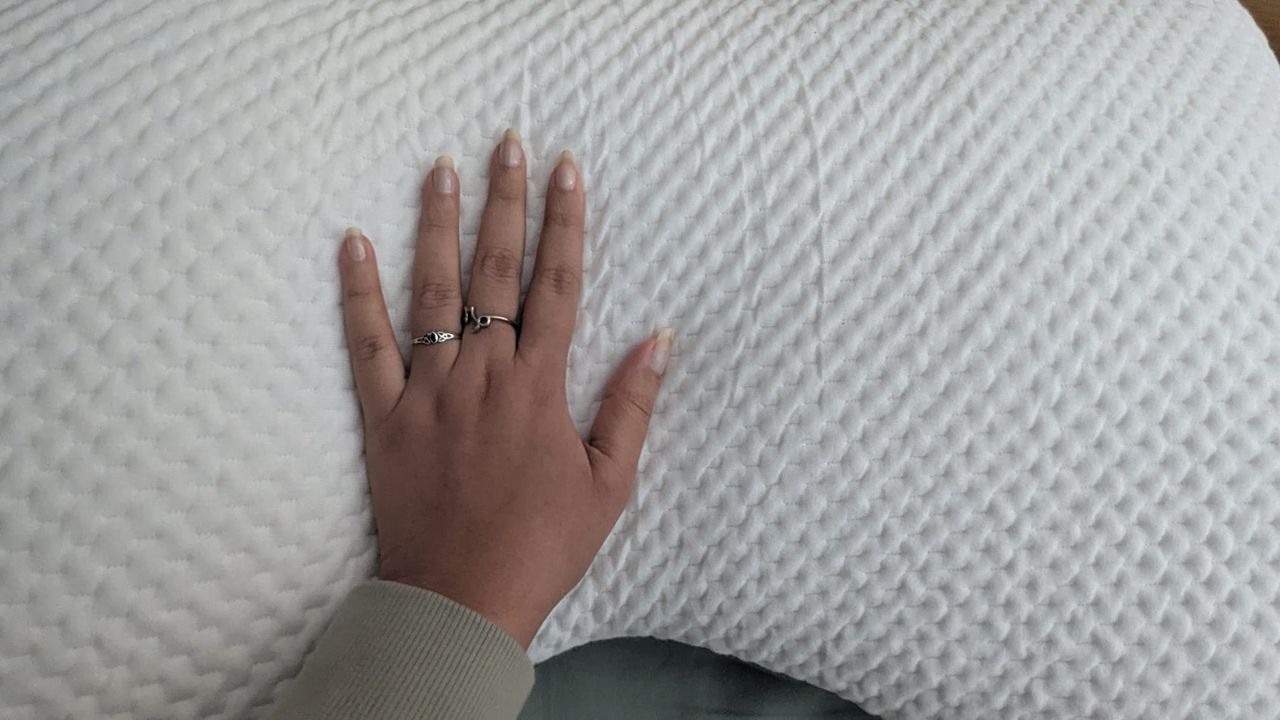 Hand placed on top of the Eli and Elm Side Sleeper Pillow