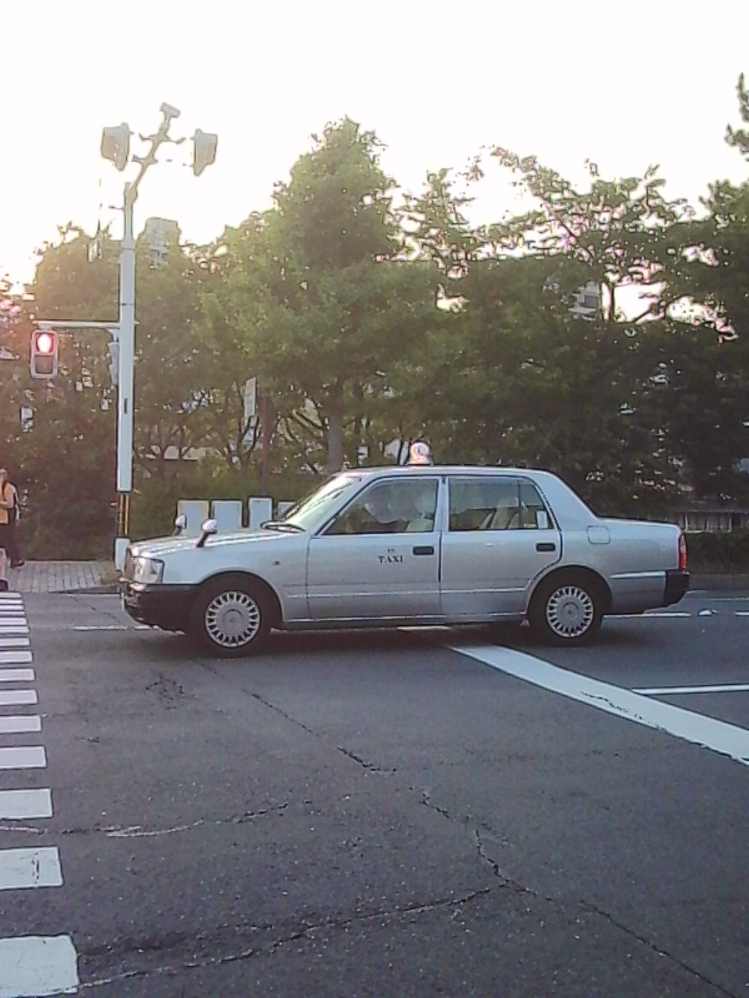 White taxi crossing a Japanese street in soft evening light.
