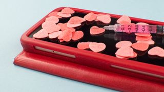 Phone covered in love hearts with syringe on top