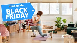 Image of woman performing a reverse lunge in her living room at home with fitness equipment around her