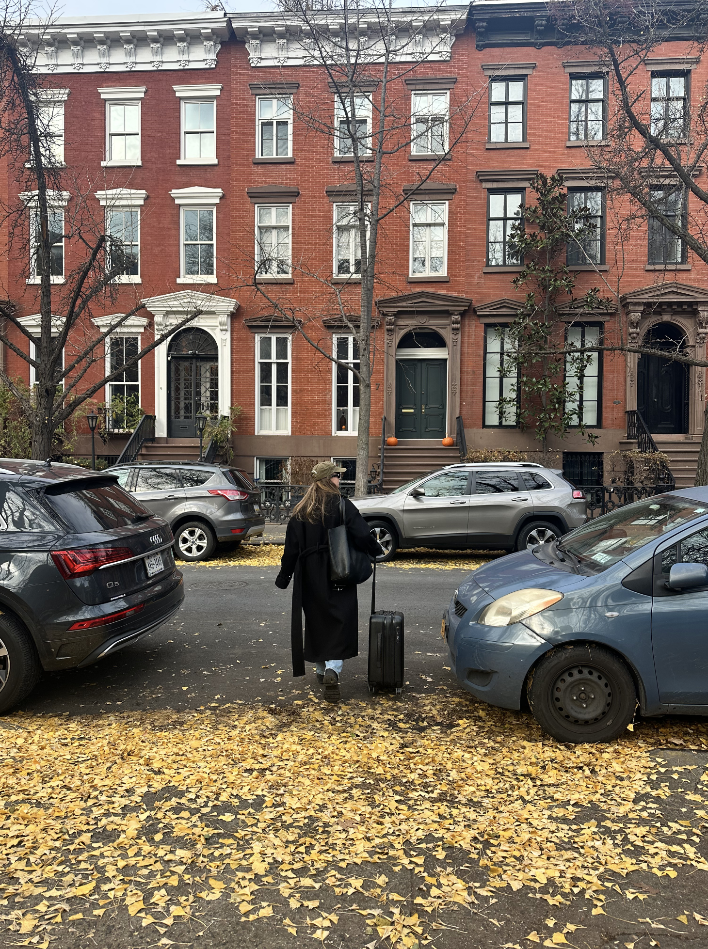 katie buckleitner crossing a fall street with a briggs and riley suitcase