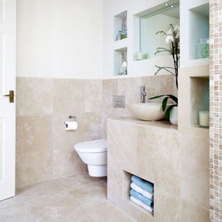 White bathroom with stone tiles and built in storage