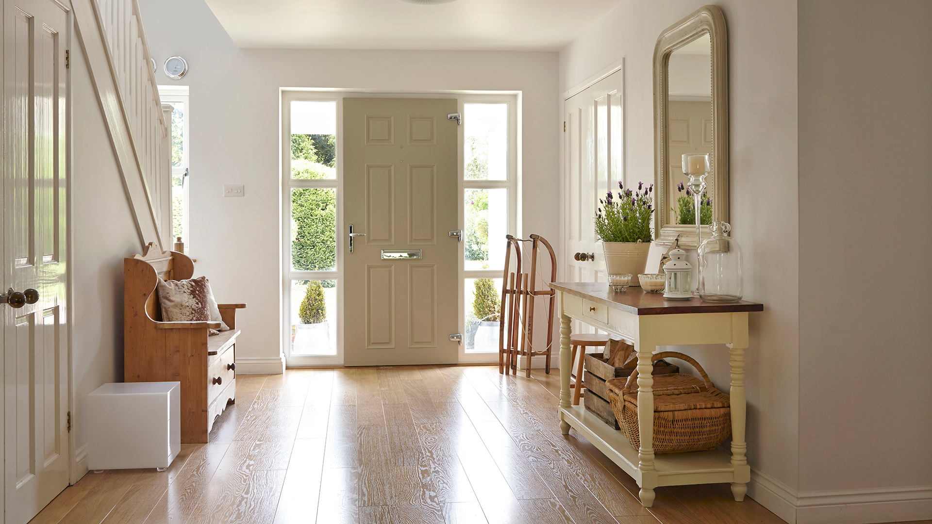 Large hallway painted in white with wooden flooring and country-style furniture