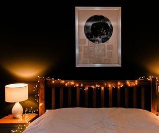 bedroom with fairy lights on wooden headboard and white side lamps